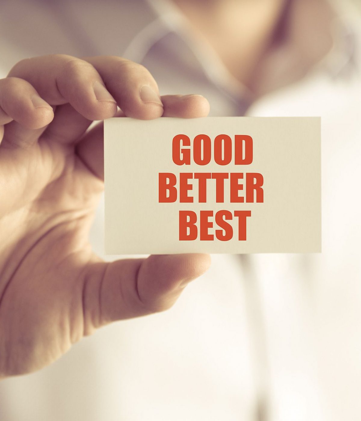Closeup on businessman holding a card with text GOOD BETTER BEST business concept image with soft focus background and vintage tone